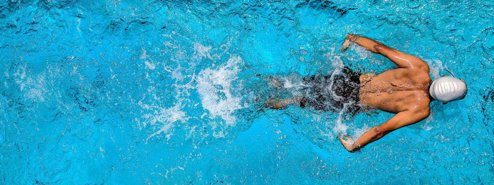 Swimmer doing freestyle stroke in bright blue pool water