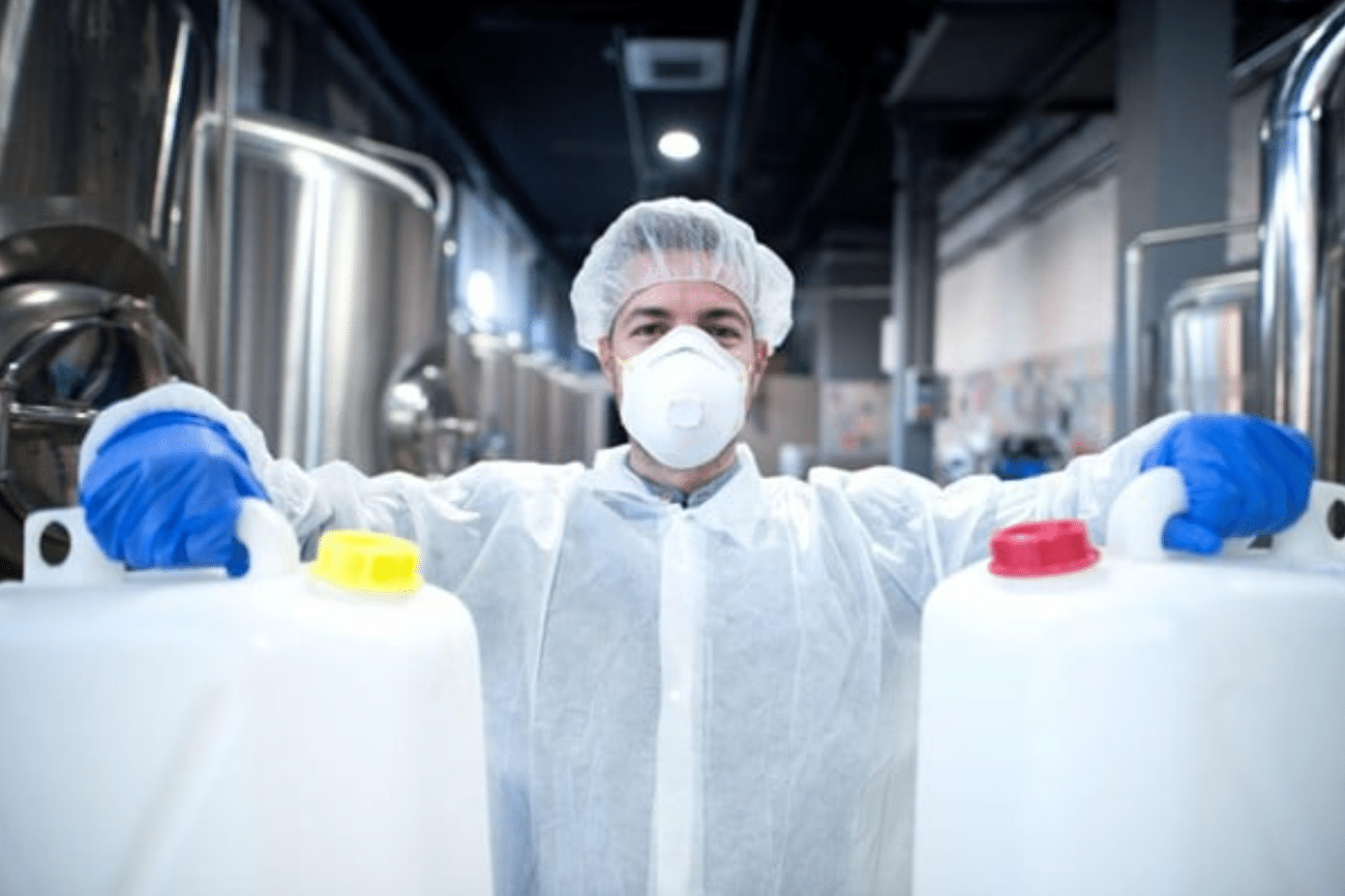 Laboratory technician in protective suit holding chemical containers