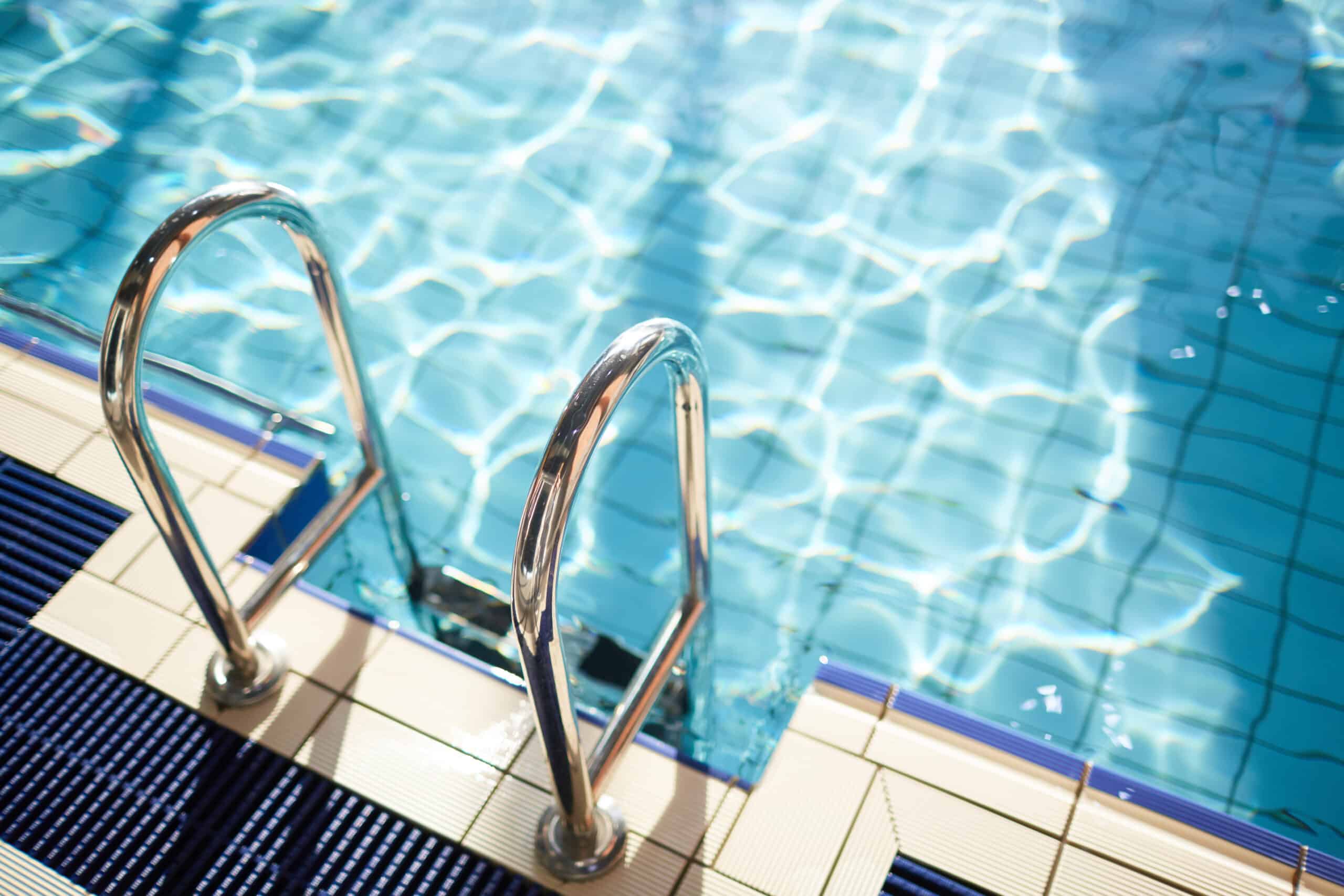 Chrome pool ladder against clear blue swimming pool water